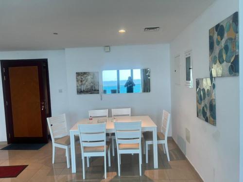 阿吉曼Sunset Beach View Holiday Homes的一间带桌子和白色椅子的用餐室