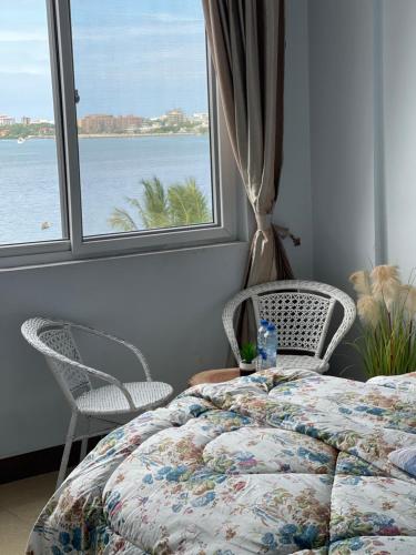 达累斯萨拉姆Arrabella Ocean View Home的一间卧室配有一张床、两把椅子和一个窗户