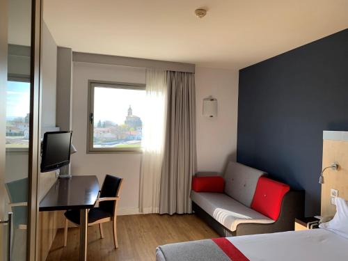 维多利亚-加斯特伊兹维多利亚快捷假日酒店的酒店客房配有一张床、一张沙发和一张书桌。