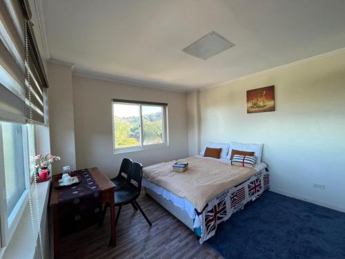 碧瑶Baguio BELL Staycation的一间卧室配有一张床、一张书桌和一个窗户。
