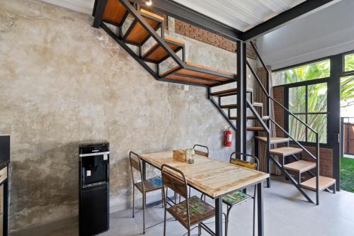 坎古Ambara U6 Loft by Hombali的客房设有木桌和螺旋楼梯。