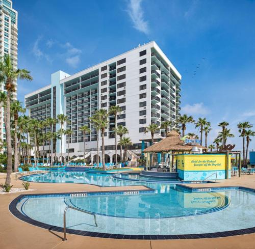 南帕诸岛Margaritaville Beach Resort South Padre Island的一座带大型游泳池的度假村,位于一座建筑前