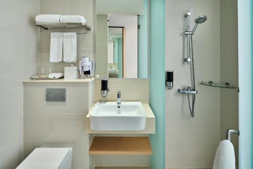 新加坡Holiday Inn Express Singapore Katong, an IHG Hotel的白色的浴室设有水槽和淋浴。