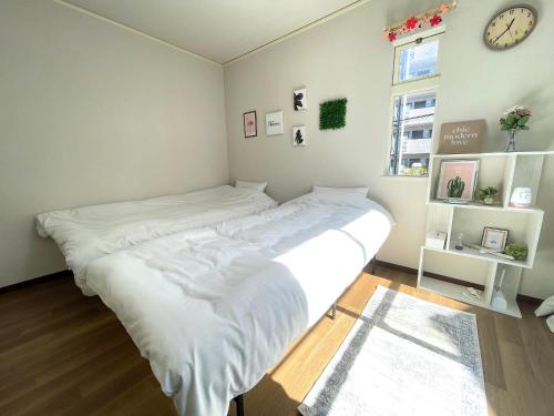 东京Gest Residence EDORIVER Airport Line Self check in的一张大白色的床,位于一个钟表的房间