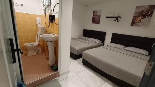 金马仑高原MUSANG ONG HOTEL的小房间设有两张床、一个水槽和一间浴室