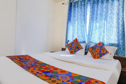 浦那FabHotel Gokul Lodge的配有蓝色窗帘的客房内的两张床
