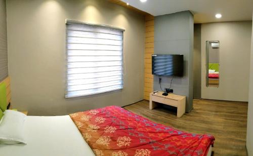 伯杰默里Hotel Rajlaxmi的一间卧室配有一张床和一台平面电视