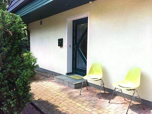 Kölpinsee auf UsedomFerienwohnung Achterhuus的两把椅子坐在房子外面,有一扇门