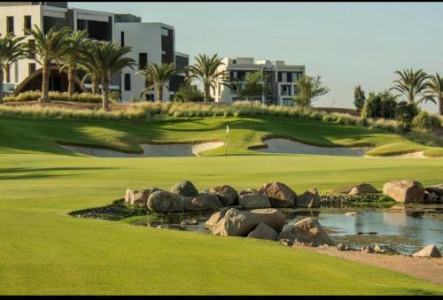 亚喀巴The Oasis Luxury Apartment的度假村内的一个高尔夫球场,有洞和岩石