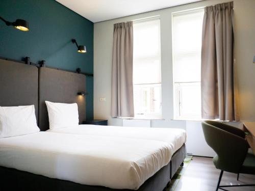 苏斯特贝赫Hotel Kontakt der Kontinenten的卧室设有一张白色大床和两个窗户。