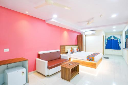 海得拉巴FabHotel Prime SYN Grand的卧室设有粉红色的墙壁、一张床和一把椅子