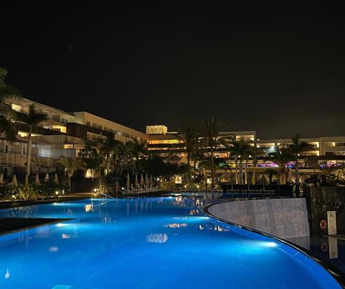 卡列罗港Hotel Costa Calero Thalasso & Spa的一座大型蓝色游泳池,晚上有楼房