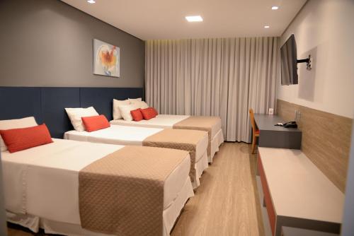 乌贝兰迪亚乌贝兰迪亚卡尔顿广场酒店的酒店客房设有三张床和一张书桌