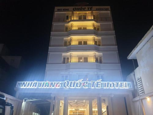 金瓯khách sạn Quốc Tế的一座高大的白色建筑,晚上有标志