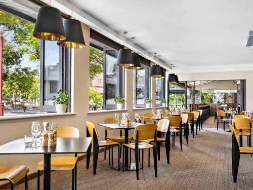 珀斯Mantra on Hay Perth的餐厅设有桌椅和窗户。