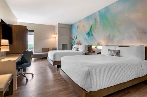 斯波坎Cambria Hotel Spokane Airport的酒店客房设有两张床,墙上挂有绘画作品