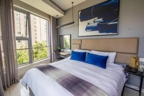 约翰内斯堡The Capital On The Park Luxury Stay的一间卧室配有一张带蓝色枕头的大床
