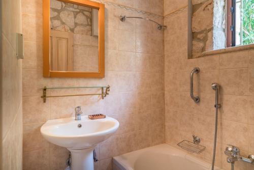 瓦西里科斯塔佩特里那米尔提斯石屋旅馆的浴室配有盥洗盆、镜子和浴缸