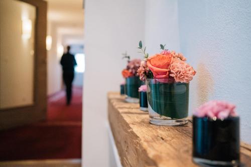 IckingKlostermaier Hotel & Restaurant的一排满鲜花的花瓶在墙上