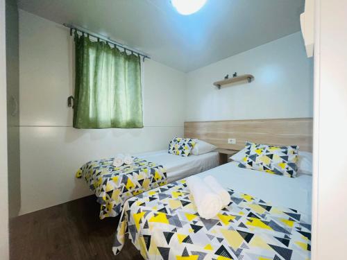 耶泽拉Mobile home Comfort Jezera Murter的客房设有两张床和窗户。