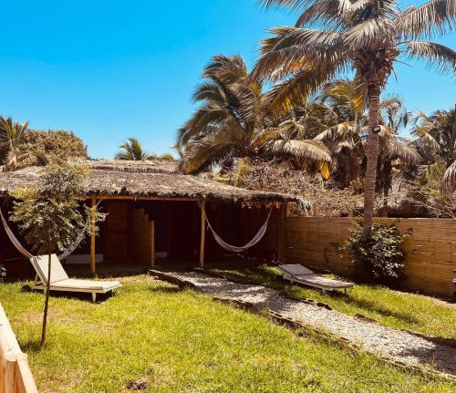 曼克拉La Nómada Digital - Máncora Playa & Piscina的棕榈树庭院内带吊床的房子