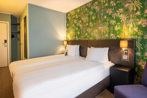 迭戈姆布鲁塞尔机场托恩酒店的一间卧室配有一张带花卉壁纸的大床