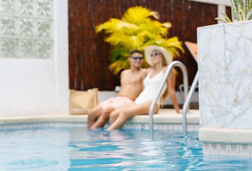檀香山Oasis Hotel Waikiki的坐在游泳池旁的男人和女人