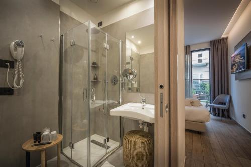 西尔米奥奈Hotel Vinci的一间带玻璃淋浴和水槽的浴室