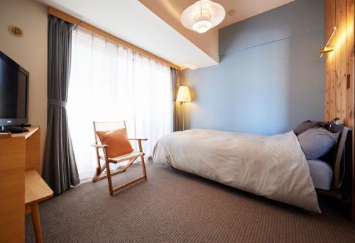 东京Shibuya apartment SHINSEN的酒店客房配有一张床、一把椅子和一台电视。