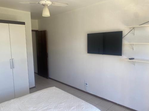 巴西利亚kitnet sudoeste proximo de comercios的卧室配有白色墙壁上的平面电视。