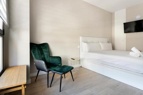 马德里Homenfun Madrid El Retiro的一间卧室配有绿色椅子和一张床