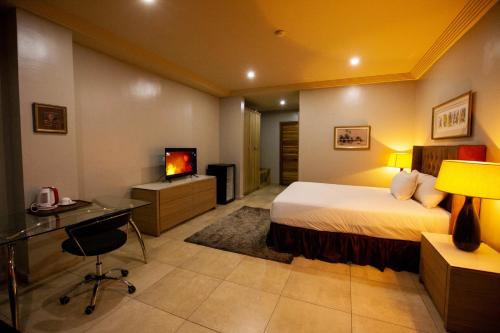哈科特港Genesis Reventon Hotel的酒店客房配有一张床、一张书桌和一台电视。