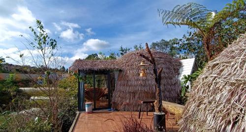 大叻Nature Homes Đà Lạt的茅草屋顶的小小屋和桌子