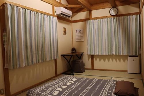 大阪Niji Homestay的卧室配有一张床,墙上挂着一个钟