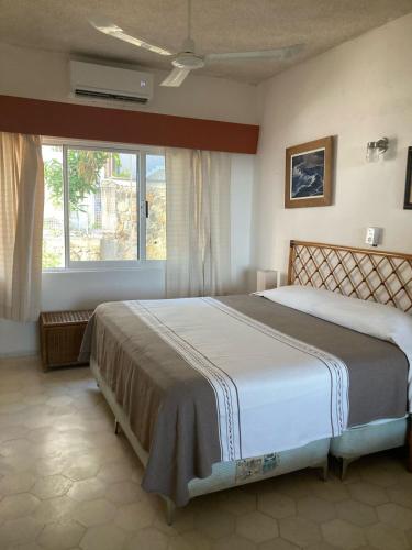 阿卡普尔科Villa Covadonga的卧室在窗户前配有一张大床