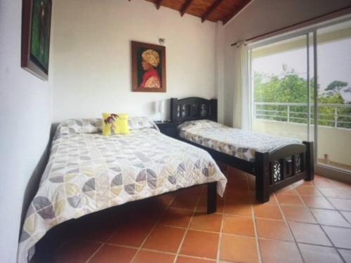 圣赫罗尼莫Finca campestre en San Jeronimo的一间卧室设有两张床和窗户。