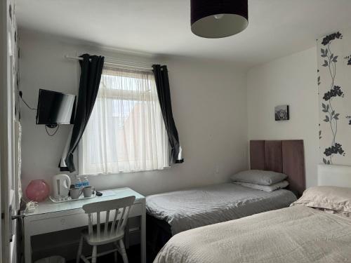 KentAylesford Guesthouse的一间卧室设有两张床、一张桌子和一个窗口。