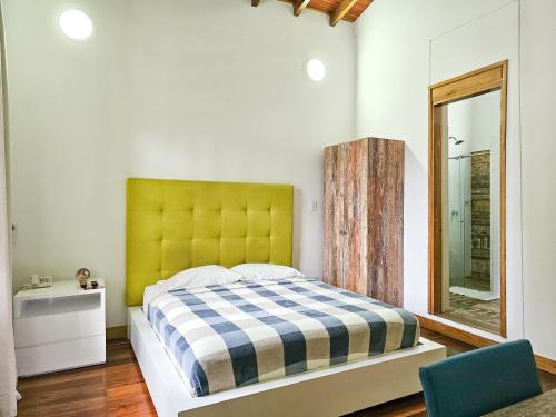 卡利La Mercedes Boutique Hostal By MH的一间卧室配有一张带黄色床头板和镜子的床