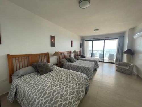 基诺湾Hermosa casa a la orilla del mar的一间卧室设有三张床和大窗户
