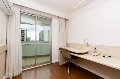 巴西利亚GS Properties - Hotel Líder的客房设有书桌和大窗户。