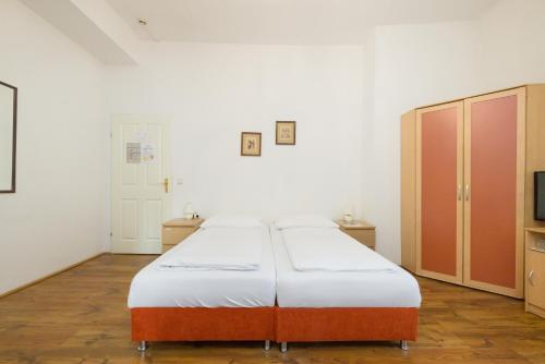 维也纳Pension Votiv的一间卧室配有一张床、橱柜和一台电视。