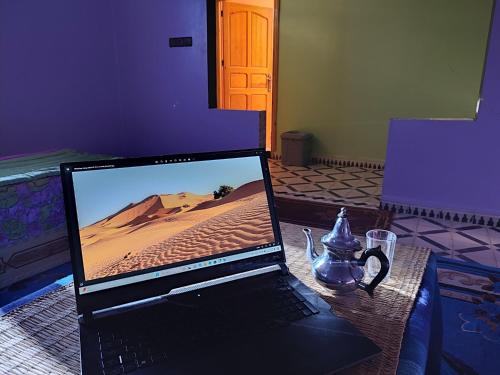 梅尔祖卡Hostel Merzouga Tifinagh的坐在桌子上的一个笔记本电脑