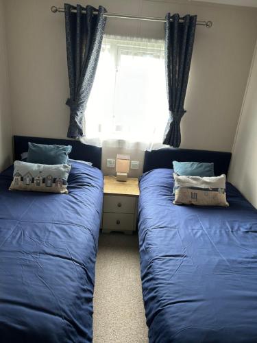 斯卡伯勒8 BIRTH LODGE ON CAYTON BAY HOLIDAY PARK的一间卧室设有两张蓝色的床和窗户
