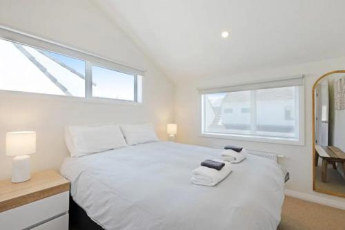 惠灵顿Lyall Bay Parade Apartment的卧室配有白色床和毛巾