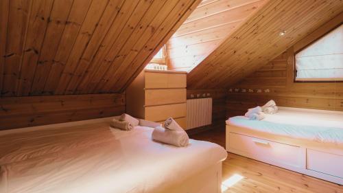 阿亨托纳Finland House Barcelona- Ideal familias的阁楼间设有两张床铺和木制天花板