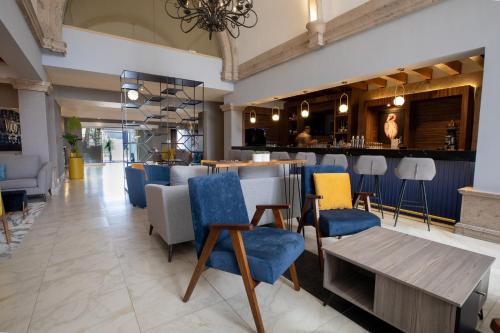 萨尔蒂约voco Saltillo Suites, an IHG Hotel的一间设有蓝色和黄色椅子的餐厅和一间酒吧