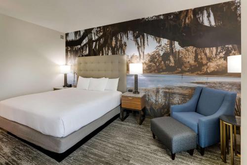 塔拉哈西Drury Plaza Hotel Tallahassee的酒店客房,配有一张床和一张蓝色椅子
