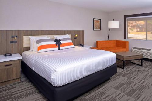 莫德斯托La Casa Modesto, Ascend Hotel Collection的一间卧室配有一张大床和一张橙色椅子