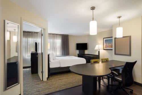达拉斯Sonesta Simply Suites Dallas Galleria的酒店客房配有一张床铺和一张桌子。