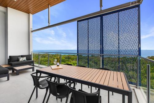 卡瓦纳华特斯Absolute Beachfront 3 Bedroom Penthouse Bokarina Sunshine Coast的一个带木桌和椅子的海景阳台